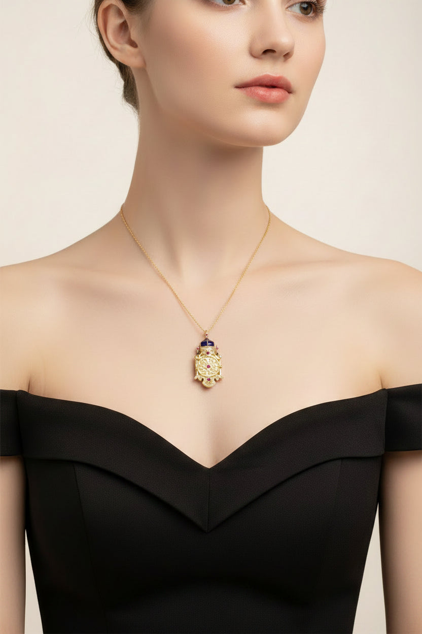 Girl in a black strapless dress wearing Gold necklace with a detailed pendant featuring blue and red stones 