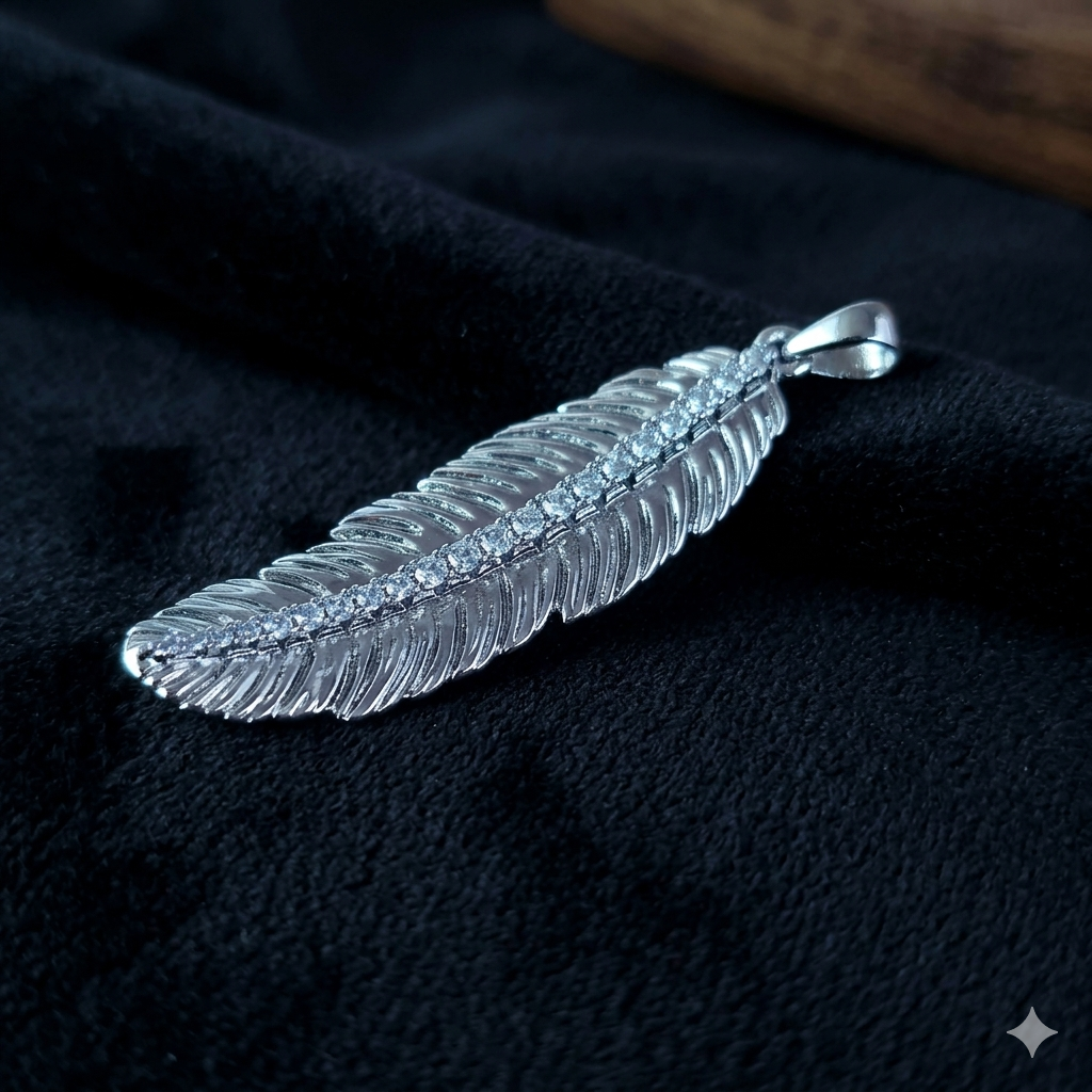 Silver feather-shaped pendant on a dark fabric background