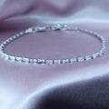 Silver bracelet with clear stones on a soft pink fabric background
