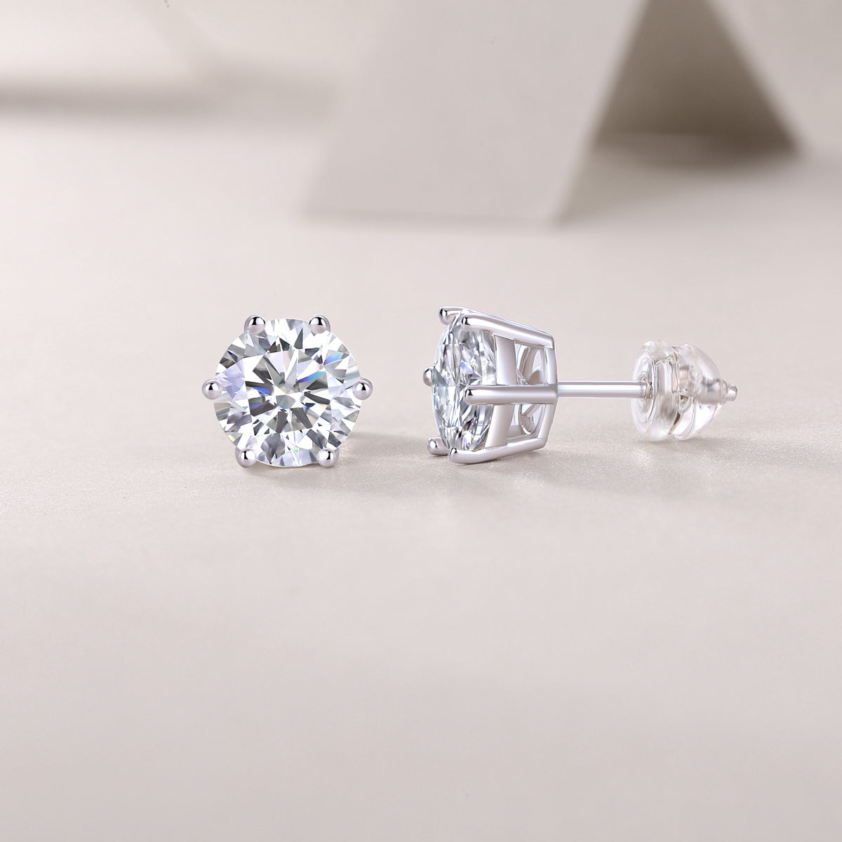 Pair of silver stud earrings with clear gemstones on a light gray background