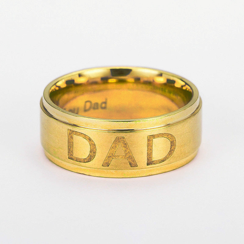 Gold ring with 'DAD' engraving on a white background