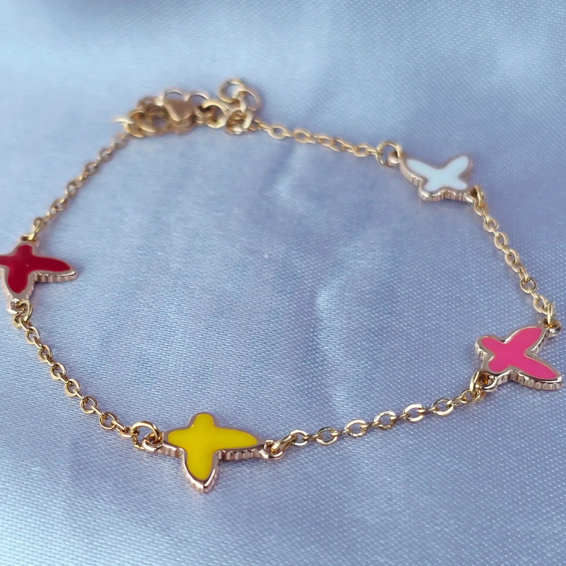 Gold bracelet with colorful butterfly charms on a light blue background