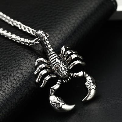 Silver scorpion pendant necklace on a dark textured surface