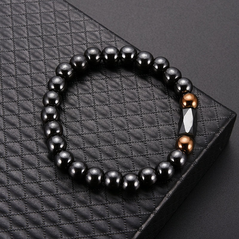 Black beaded bracelet with brown and white accents on a textured black surface