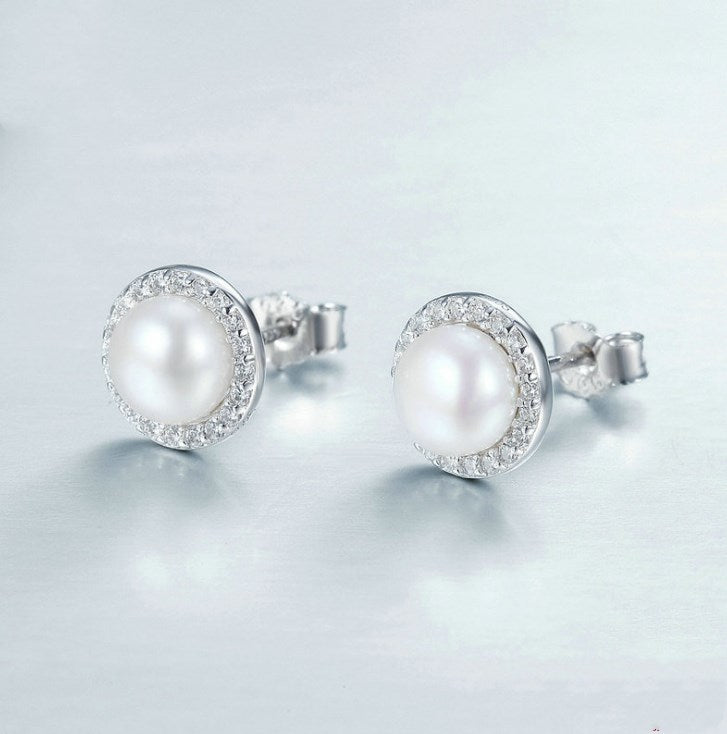 Pearl earrings with silver setting on a light gray background