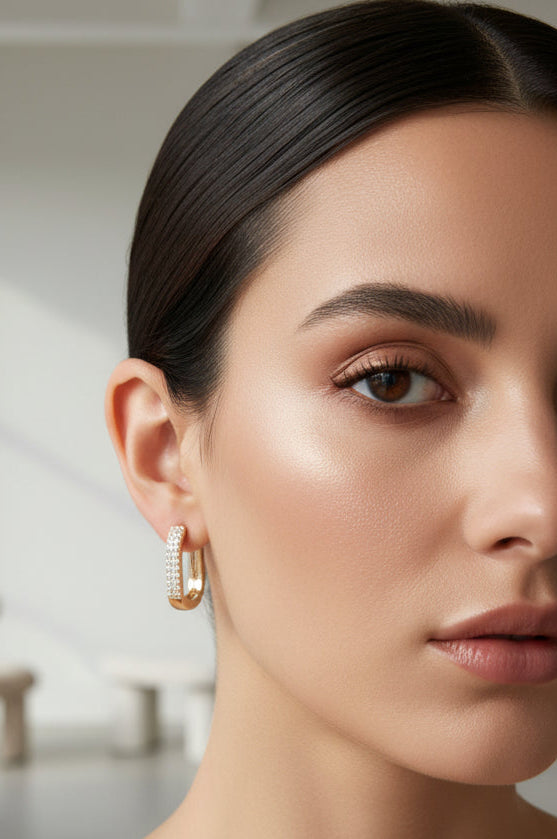 Close-up of a woman wearing gold hoop earrings with a neutral background